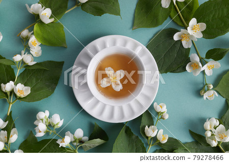 cup of tea with jasmine flowers on green background. Flat lay, top view cup of tea with jasmine flowers on green background. Flat lay, top view 79278466