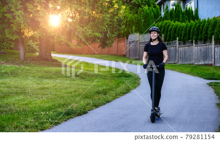 Caucasian Adult Woman riding an electric scooter on a path 79281154
