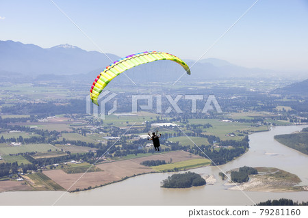 Adventurous Woman Flying on a paraglider around the Canadian Mountain Landscape 79281160