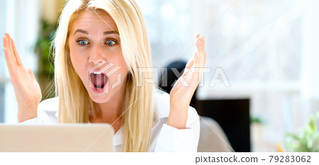 Surprised young woman sitting at her desk 79283062