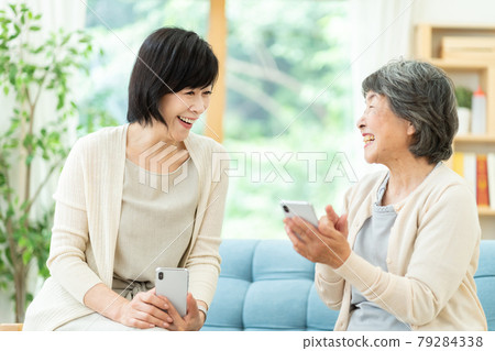 一邊看手機一邊交談的父母和孩子、婆婆、母子、老年婦女和兩個中年婦女 79284338