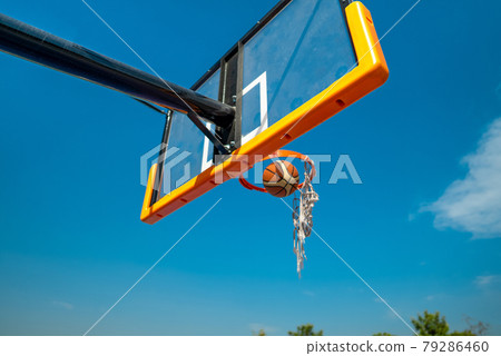 Basketball ball falling through old net. Blue sky on background 79286460