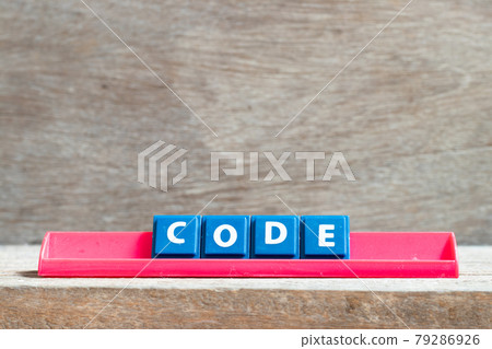 Tile letter on red rack in word code on wood background Tile letter on red rack in word code on wood background 79286926