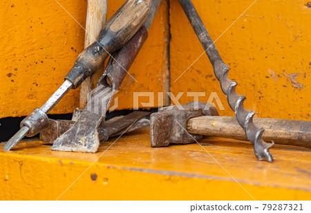 rusty, old, worn out carpenter tools for domestic farming lie on the wooden steps of a private house rusty, old, worn out carpenter tools for domestic farming lie on the wooden steps of a private house 79287321