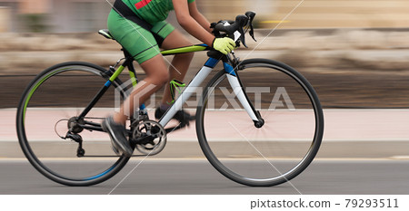 Cycling rider competing in the youth class, motion blur of a bike race with the bicycle and rider at high speed. Panning technique used Cycling rider competing in the youth class, motion blur of a bike race with the bicycle and rider at high speed. Panning technique used 79293511