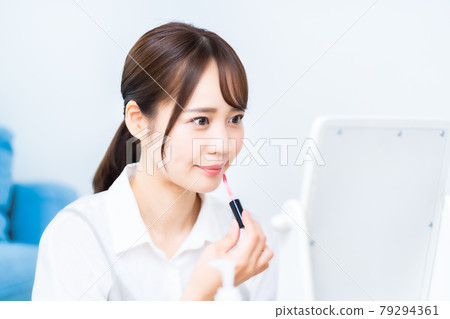 一個女人看著鏡子時塗口紅 一個女人看著鏡子時塗口紅 79294361