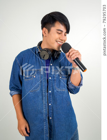 Young asian man in blue jean singing with microphone. Portrait on white background with studio light. Close Up 79295703