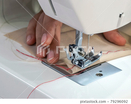 Fashion designer room, The dressmaker elaborately made a red silk thread pattern on a fine beige fabric. Close up Fashion designer room, The dressmaker elaborately made a red silk thread pattern on a fine beige fabric. Close up 79296092