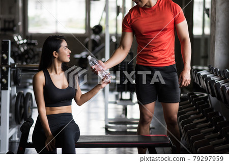 man give water to young fit woman in gym 79297959