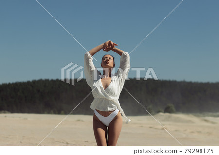 Dreamy young woman in white wear standing in nature Dreamy young woman in white wear standing in nature 79298175