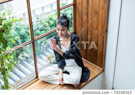 一個年輕女子在家裡看智能手機 79298563