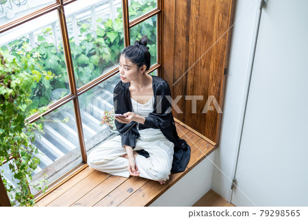 一個年輕女子在家裡看智能手機 79298565