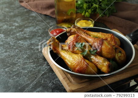 Concept of delicious eating with pan of roast chicken drumsticks on black smokey table 79299313