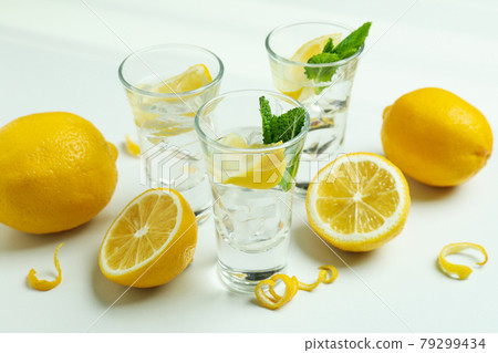 Shots of vodka and lemons on white background Shots of vodka and lemons on white background 79299434