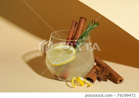 Glass of lemonade with cinnamon and rosemary on beige background Glass of lemonade with cinnamon and rosemary on beige background 79299472