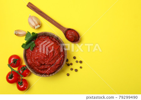 Bowl of tomato paste and ingredients on yellow background Bowl of tomato paste and ingredients on yellow background 79299490