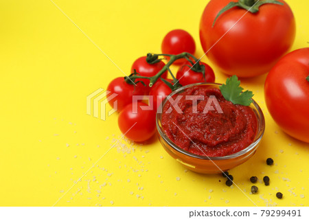 Bowl of tomato paste and ingredients on yellow background Bowl of tomato paste and ingredients on yellow background 79299491