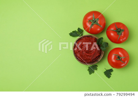 Bowl of tomato paste and tomatoes on green background Bowl of tomato paste and tomatoes on green background 79299494