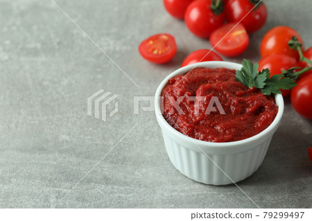 Bowl of tomato paste and tomatoes on gray textured background Bowl of tomato paste and tomatoes on gray textured background 79299497