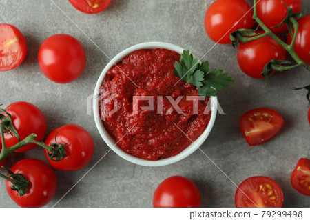 Bowl of tomato paste and tomatoes on gray textured background Bowl of tomato paste and tomatoes on gray textured background 79299498