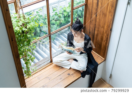 A young woman reading by the window 79299929