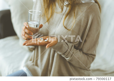 Close-up woman holding pills time to take medications, cure for headache, high blood pressure or cholesterol level remedy pain killer drugs. Stay at home concept during Coronavirus pandemic and self 79300117