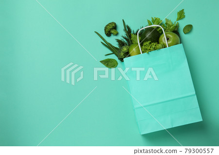 Paper bag with green vegetables on mint background Paper bag with green vegetables on mint background 79300557