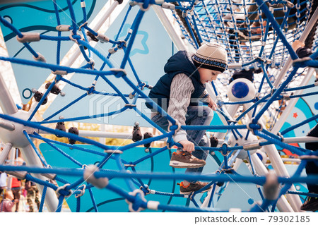 Little boy plays in the playground on the rope road 79302185