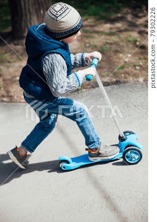 Little boy rides a scooter on the roads in the playground Little boy rides a scooter on the roads in the playground 79302226