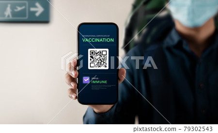 Health Vaccine Passport for Coronavirus or Covid-19. Traveller Presenting Mobile Phone Screen with Vaccination in Immune Status to Certificated International Traveling in Airport Health Vaccine Passport for Coronavirus or Covid-19. Traveller Presenting Mobile Phone Screen with Vaccination in Immune Status to Certificated International Traveling in Airport 79302543