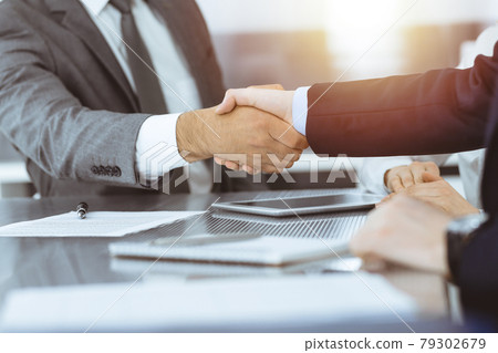 Handshake as successful negotiation ending, close-up. Unknown business people shaking hands after contract signing in modern office Handshake as successful negotiation ending, close-up. Unknown business people shaking hands after contract signing in modern office 79302679