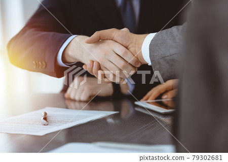 Handshake as successful negotiation ending, close-up. Unknown business people shaking hands after contract signing in modern office Handshake as successful negotiation ending, close-up. Unknown business people shaking hands after contract signing in modern office 79302681