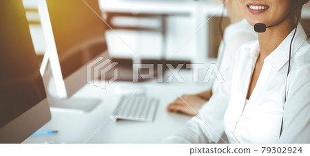 Unknown female customer service representative iconsulting clients online using headset.close-up. Sunny Call center 79302924