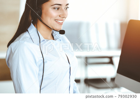 Brunette female customer service representative using headset and consulting clients online. Call center Brunette female customer service representative using headset and consulting clients online. Call center 79302930