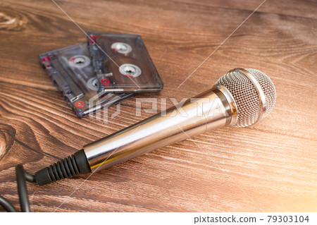 A silver analog microphone sits next to old cassette tapes 79303104