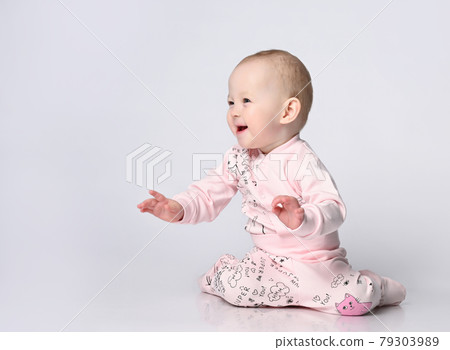 Little cute baby sitting on the floor in the 79303989