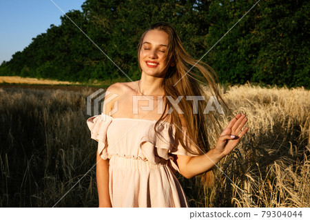 Nature mental health benefits. Connection to Nature, time outside, outdoor day off. Nature deficit disorder. Young woman enjoying nature on wheat field at sunset. 79304044