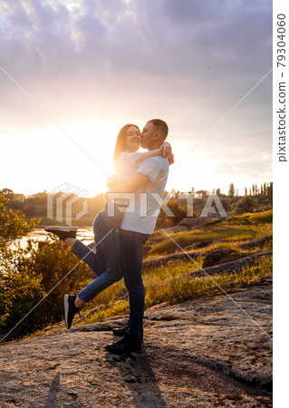 Romantic getaway, Romantic Destinations to Honeymoon, solo travel. Couple in love silhouette on nature sunset yellow and purple sky background. Young couple enjoying the sunset in the meadow. 79304060