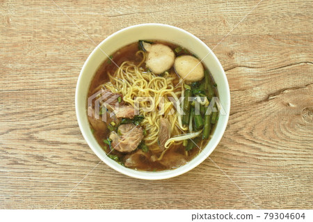 Chinese egg noodles topping braised pork and meatball in brown soup on bowl 79304604