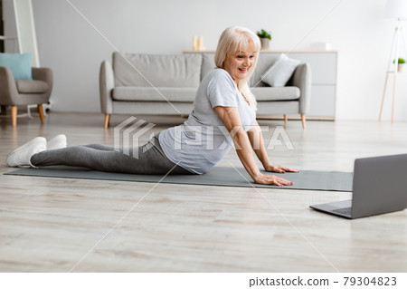 Senior woman stretching back on mat with pc 79304823