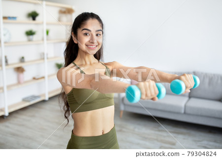 Home training concept. Active Indian lady working out with dumbbells indoors 79304824