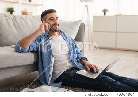 Smiling jew man working and talking on cellphone at home Smiling jew man working and talking on cellphone at home 79304864