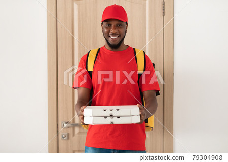 Black deliveryman holding pizza boxes and posing at door Black deliveryman holding pizza boxes and posing at door 79304908