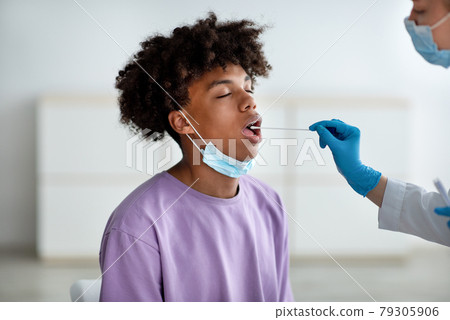 Oral coronavirus PCR test. Doctor using sterile swab to take covid virus sample from black teenager at clinic 79305906