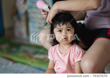 Mother and little girl drying hair with hairdryer after having bath 79307670