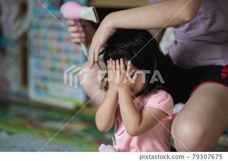 Mother and little girl drying hair with hairdryer after having bath 79307675