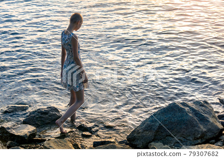 teen girl in a dress by the sea enters the water teen girl in a dress by the sea enters the water 79307682