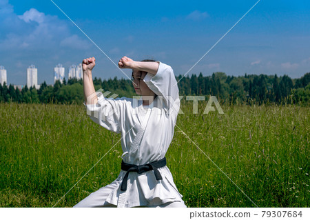 teen girl training karate kata outdoors, performs the haiwan uke movement 79307684