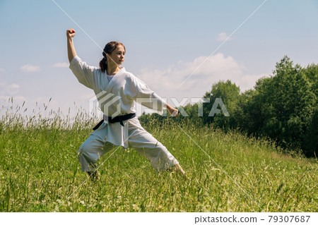 teen girl practicing karate kata outdoors in kokutsu-dachi stance 79307687