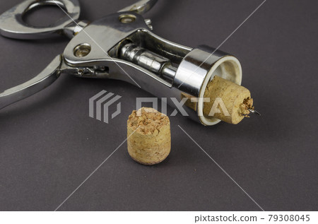 Old corkscrew and broken cork on a gray background. 79308045